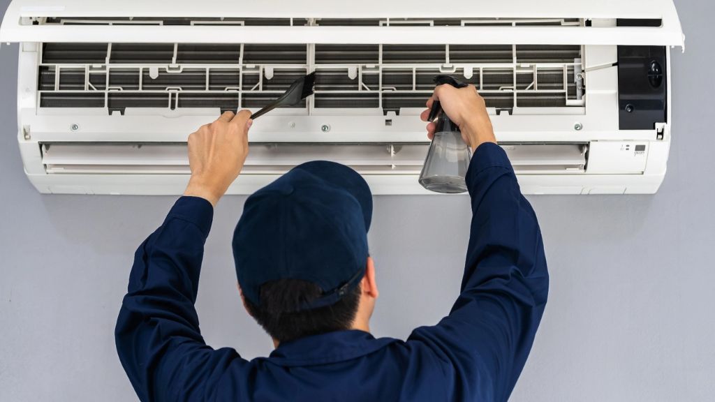 Technician cleaning an air conditioner